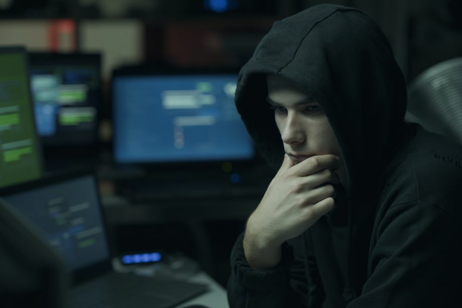 Cool hacker with hoodie working with computers